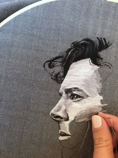 a hand holding a piece of paper with a drawing of a man's face on it