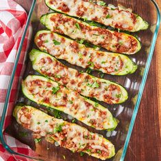 stuffed zucchini boats in a glass dish on a wooden table with red and white checkered cloth