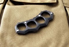 a black bottle opener sitting on top of a tan jacket with holes in the middle