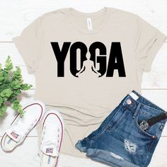 a t - shirt with the word yoga on it next to ripped jeans and sneakers