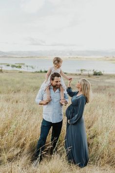 a man, woman and child standing in tall grass