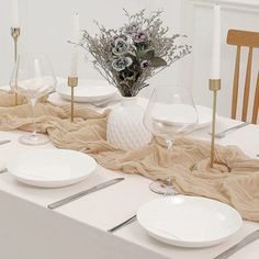 the table is set with white plates and silverware