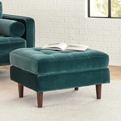 a green chair and footstool in front of a brick wall with a book on it