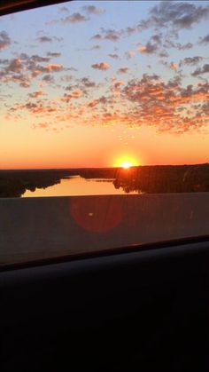 the sun is setting over a body of water as seen from inside a train window