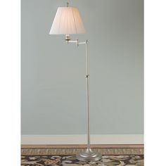 a floor lamp with a white shade on it's base and a rug underneath