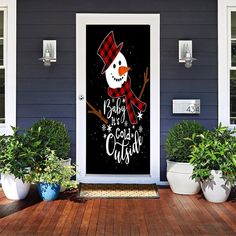 a snowman is on the front door of a blue house with potted plants