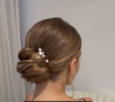 a woman with her hair in a low bun and pearls on the back of her head