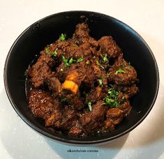 a bowl filled with meat and vegetables on top of a white countertop next to a fork