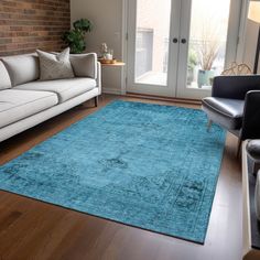 a living room filled with furniture and a blue rug on top of a hard wood floor