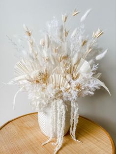 a white vase filled with feathers on top of a wooden table