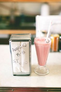 a pink drink sitting on top of a table next to a carton of milk