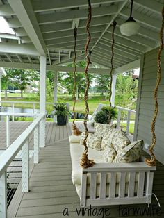 a porch swing with pillows on it