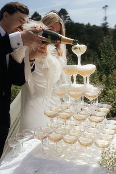 a bride and groom are pouring champagne into wine glasses