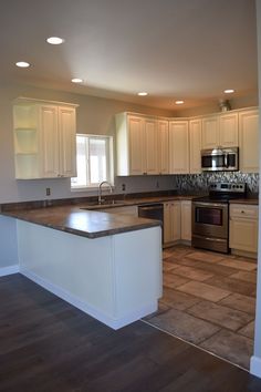 an empty kitchen with white cabinets and stainless steel appliances in the middle of the room