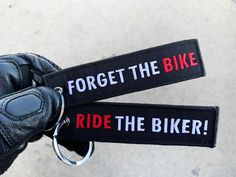 two black leather gloves with red and white text on them that say, forget the bike ride the biker