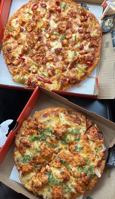 two pizzas sitting on top of cardboard boxes next to each other with toppings