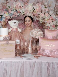 a woman standing next to a table filled with pink and gold items, including a teddy bear