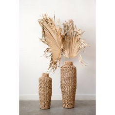 two vases with dried plants in them on a table next to a wall and floor