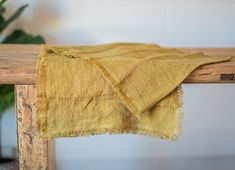 an old yellow cloth is sitting on a wooden table next to a potted plant