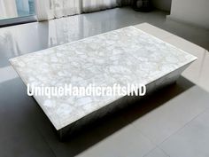 a white marble coffee table sitting on top of a tile floor next to a window