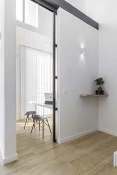 an empty room with white walls and wooden floors, along with a small dining table