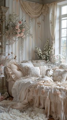 a white bed sitting in a bedroom next to a window filled with lots of flowers