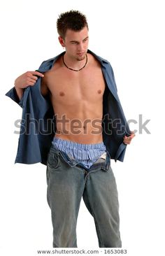 a shirtless man in jeans is holding his jacket over his shoulder and looking at the camera