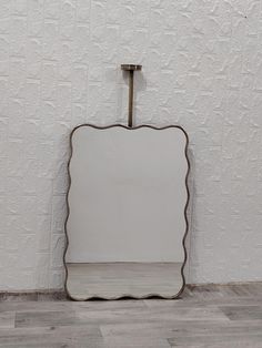 a white square shaped mirror sitting on top of a wooden floor next to a wall