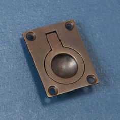 a metal square with a hole in the middle on a blue surface that appears to be part of a machine