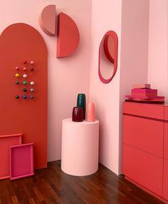 a room with pink walls and various items on the floor, including a round mirror