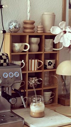 an espresso machine sitting on top of a counter next to a wooden shelf