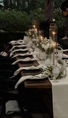 a long table is set up with candles and place settings for dinner guests to enjoy