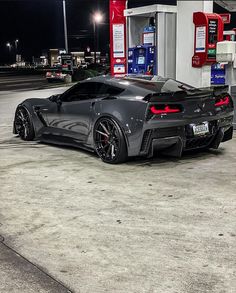 a black sports car parked in front of a gas station