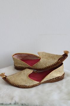 "Vintage Indian theme inspired slippers. The slippers/flats are a gold tone brocade design. The inside is lined in a bright pink fabric. The toe is curved up and has a tassel detail. The shoes are in good condition. Size: 7.5 Inside Length: 9.5\" | Inside Width: 3.25\" | Outside Heel Length: .75\" | Inside Heel Length: .25\" Unless otherwise stated all vintage items are used and may have minor to moderate wear or discoloration considering the age of the item. Most items have been hand washed, sp Gold Slip-on Loafers For Galas, Gold Round Toe Loafers For Galas, Traditional Formal Slip-on Slippers, Gold Slip-on Wedding Shoes, Gold Slip-on Loafers With Rubber Sole, Gold Slip-on Shoes For Formal Wedding, Gold Slip-on Wedding Shoes For Formal Wear, Gold Almond Toe Loafers For Galas, Gold Flat Wedding Shoes For Festivals