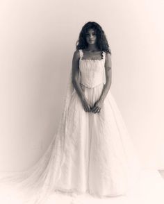 a black and white photo of a woman in a wedding dress with her hands on her hips