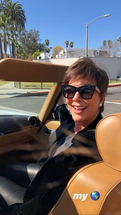 a woman sitting in the driver's seat of a car wearing sunglasses and smiling