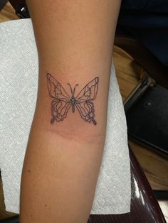 a woman's arm with a tattoo of a butterfly on the back of it