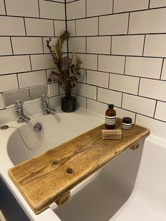 a wooden shelf sitting on top of a bath tub next to a vase with flowers