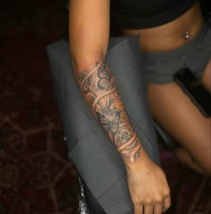 a woman with a tattoo on her arm holding a piece of luggage and looking at the camera