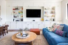 a living room filled with furniture and a flat screen tv mounted on the wall above a wooden coffee table