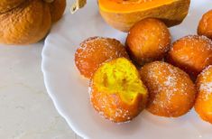 a white plate topped with donuts covered in powdered sugar next to pumpkins