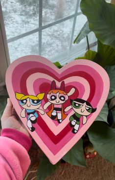 the powerpuff girls heart shaped paper cutout is held up by a child's hand