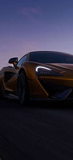 an orange sports car driving down the road at night with its lights on and headlights on