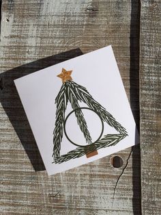 a card with a christmas tree on it sitting on top of a piece of wood