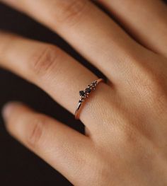 a woman's hand with a diamond ring on top of her finger and black diamonds in the middle