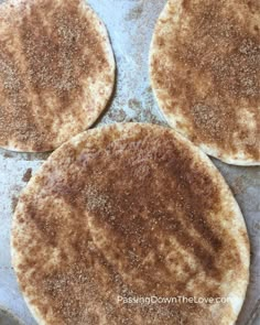 four uncooked pita breads sitting on top of a baking pan covered in seasoning