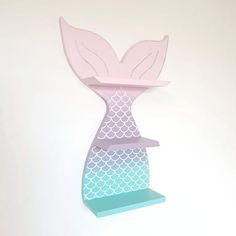 a paper cut out of a mermaid tail on a shelf in the shape of a vase