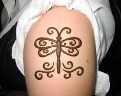 a woman's arm with a tattoo design on the back of her leg, which is shaped like a dragonfly