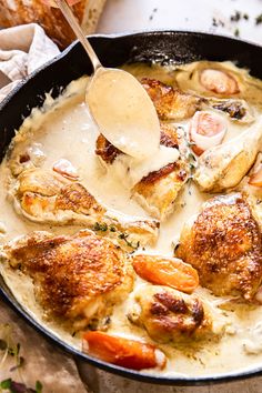 a pan filled with chicken and carrots covered in gravy next to bread