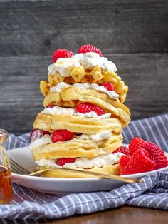 a stack of waffles topped with whipped cream and raspberries